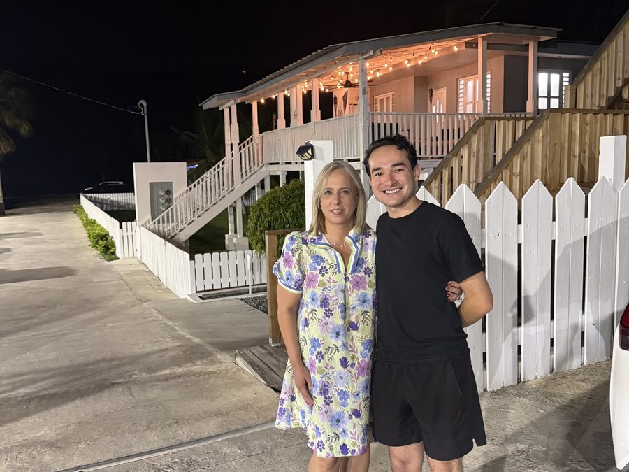 Enrique José Navedo and Dr. Lisa standing together at night in front of a lit wooden porch in Puerto Rico.